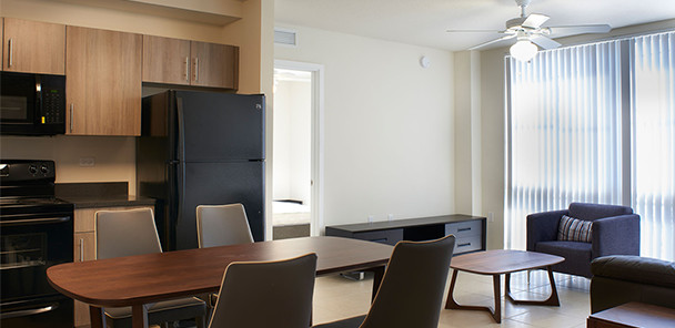 Open concept living room and kitchen-dining area with wood cabinets and black appliances.